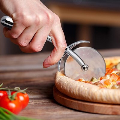 maint tient couteau a pizza et coupe pizza sur planche avec tomates