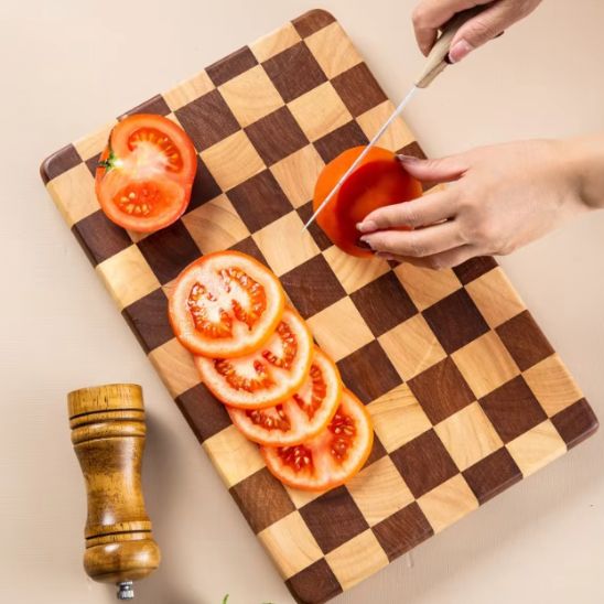 femme coupe tomate sur planche à découper bois damier