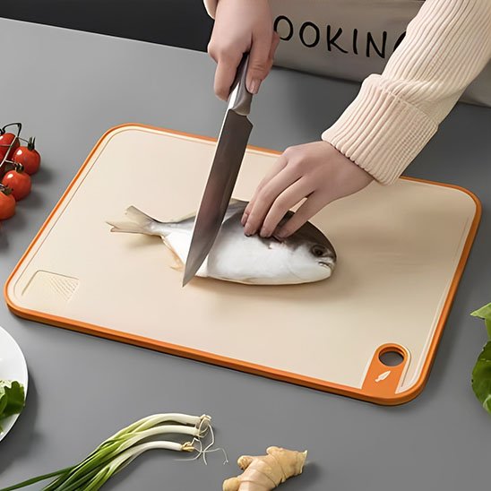 personne coupe poisson sur planche à découper 