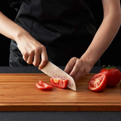 personne coupe tomate sur planche à découper bois
