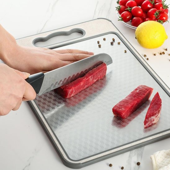 personne coupe viande sur planche à découper en inox