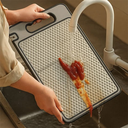 personne passe sous l'eau du robinet une planche à découper en inox