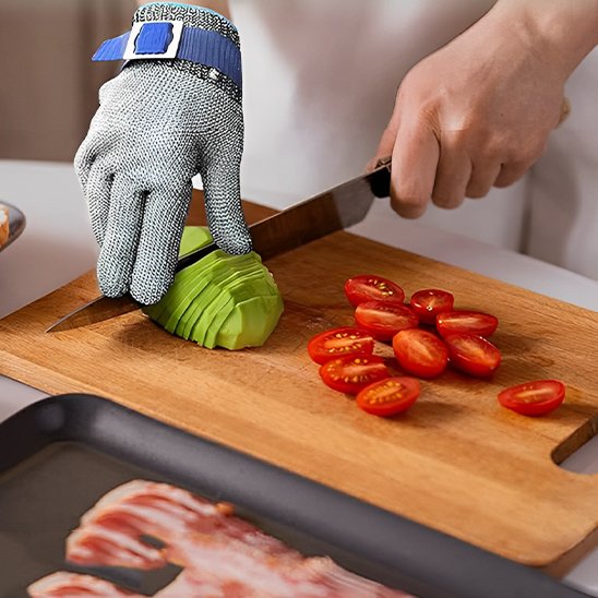 personne utilise gant anti coupure pour couper un avocat sur une planche